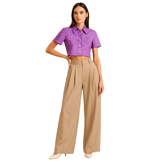 FEMALE MODEL WEARING BEIGE DOUBLE PLEATED LOOSE STRAIGHT FROM HIPS  AND EXTRA WIDE LEGS. TROUSER HAVE CROSS POCKETS AT FRONT ,BELT LOOPS . MODEL IS POSING WITH ONE HAND ON WAIST AND OTHER HAND STRAIGHT. MODEL IS WEARING CREAM HIGH HEELS WITH PURPLE PRINTED CROP SHIRT
