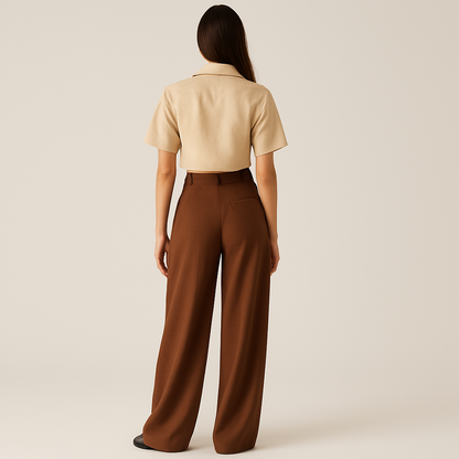 BACK IMAGE OF FEMALE MODEL WEARING BROWN COLOUR LOOSE STRAIGHT FIT WIDE LEGS TROUSER WITH BELT LOOPS AND ONE CUT POCKET AT BACK. MODEL IS WEARING BEIGE COLOUR CROP SHIRT